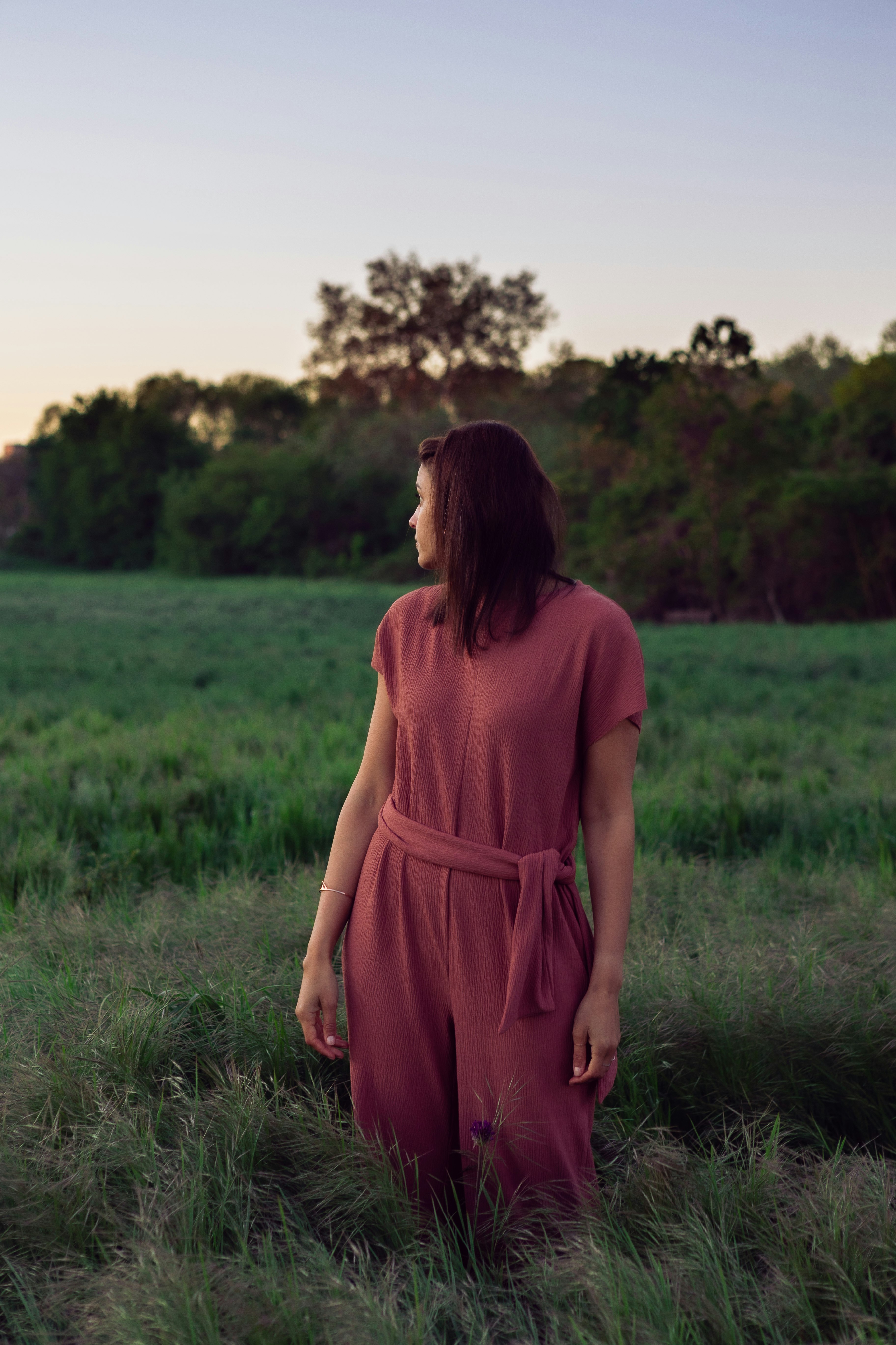 woman in pink dress standing on green grass field during daytime